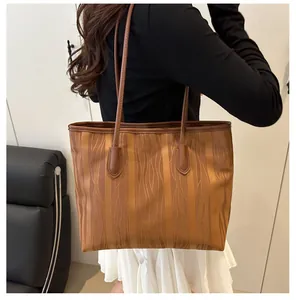 Brown tote bag with wave texture and long straps worn on shoulder by a model