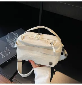 Close-up of cream crossbody bag featuring dual zippers and adjustable wide shoulder strap