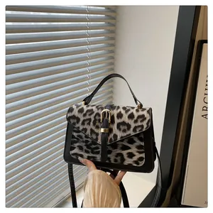 Detail of leopard print handbag with V-shaped flap and gold metal buckle hardware