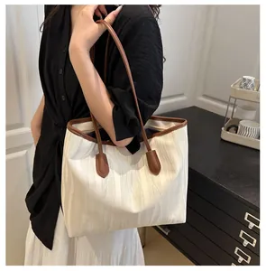 Detail view of stylish beige tote bag with wavy texture and brown handles on a model