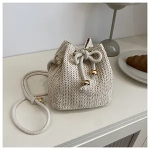 Dettaglio borsa a secchiello in paglia intrecciata beige con chiusura a coulisse dorata