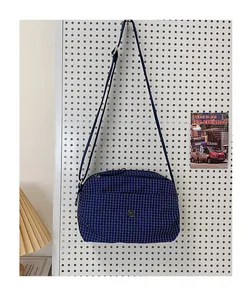Détail du sac bandoulière en toile à carreaux bleu marine avec fermetures éclair argentées