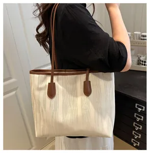 Detail of a beige canvas tote with 3D wavy textures and dark brown leather straps