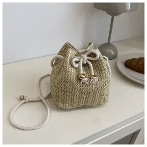 Dettaglio della borsa a secchiello intrecciata con chiusura a coulisse e nappine dorate