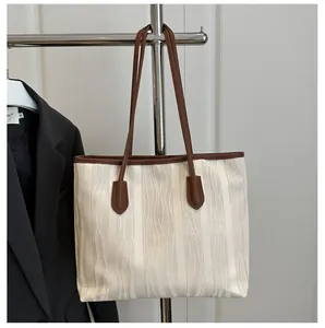 Detailed view of cream-white tote bag with wave texture and contrast brown leather straps