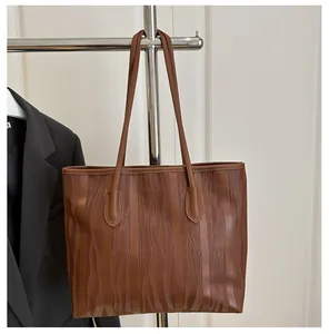 Detailed view of brown tote bag with wavy ripple texture on smooth synthetic leather