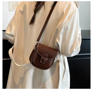 Dettaglio di una borsa a tracolla marrone scuro vintage con patta goffrata e cinturino