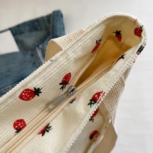 Detalle de la cremallera plateada en el bolso tote de pana con estampado de fresas