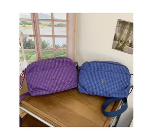 Gros plan de sacs bandoulière en toile à carreaux violet et bleu sur une table