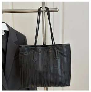 Close-up of black tote bag featuring vertical striped mesh texture and leather straps