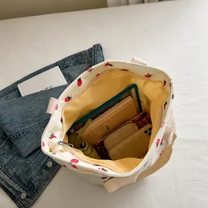 Vista superior que muestra la gran capacidad del bolso tote de pana con fresas e iPad