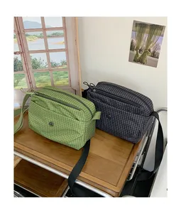 Vue détaillée de sacs bandoulière en toile à carreaux vert et gris sur étagère