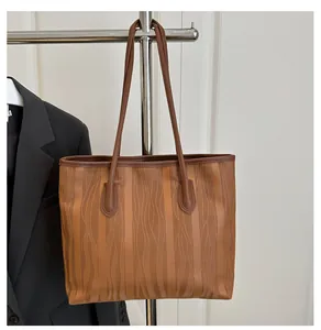 Detail of brown tote bag showing vertical wavy texture and sleek faux leather finish