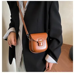 Dettaglio della borsa a sella marrone in pelle PU con fibbia logata e cuciture di qualità