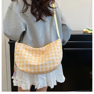 Detail of yellow plaid crossbody bag featuring cute cartoon embroidery and adjustable strap
