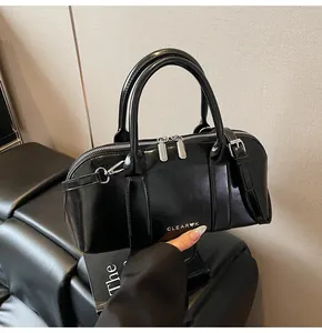 Detalle de bolso Boston negro brillante con cremalleras plateadas y logo bordado