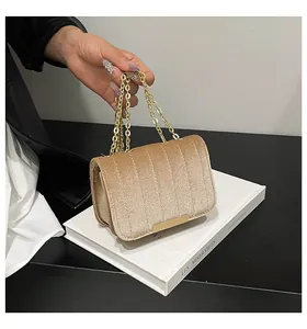 Detailed view of champagne velvet crossbody bag with vertical quilting and gold chain strap