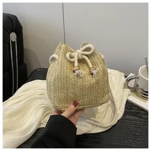Dettaglio della borsa a secchiello in paglia intrecciata con trama a V e lacci dorati