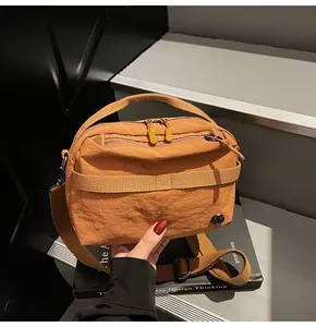 Detail of ginger yellow crossbody camera bag with dual zippers and woven strap