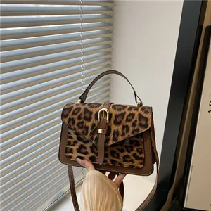 Chic leopard print crossbody bag with brown leather trim and gold buckle detail