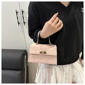 Détail d'un sac à bandoulière rose en cuir verni brillant avec motifs gaufrés et fermoir doré