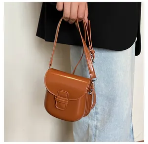 Dettaglio della piccola borsa a tracolla marrone vintage con patta lucida e fibbia