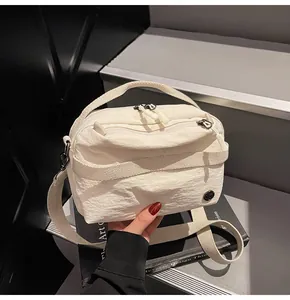 Detail of cream white nylon crossbody bag with pleated texture and metal logo