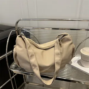 Minimalist beige nylon hobo shoulder bag with a crescent shape and wide strap