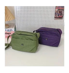 Détail de sacs bandoulière en toile à carreaux verts et violets avec bandoulière réglable