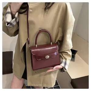 Dettaglio della borsa in pelle lucida bordeaux con fibbia girevole in oro vintage