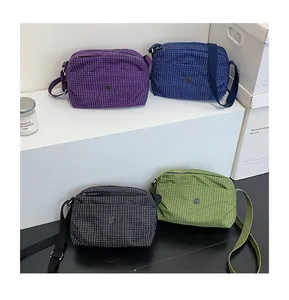 Détail de quatre sacs bandoulière en toile à carreaux en violet, bleu, noir et vert d'été