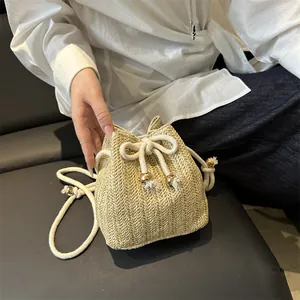 Secchiello estivo in paglia intrecciata con coulisse e nappe su modella donna