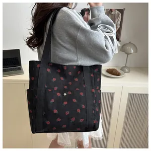 Detail of strawberry print corduroy tote bag showing textured fabric and side pocket