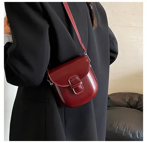 Dettaglio della borsa a tracolla rosso scuro indossata dalla modella con blazer