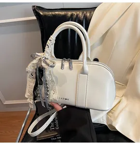 Detalle de bolso crema con cinta de encaje, dije plateado y logo LEAR♥K en el asiento