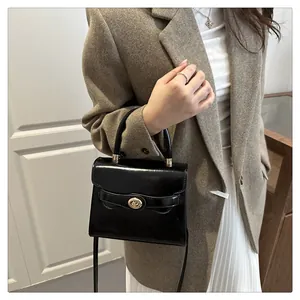 Dettaglio della borsa a mano in pelle lucida nera con elegante chiusura girevole dorata e manico