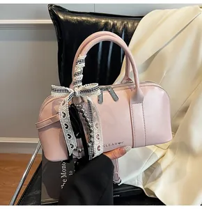 Detalle del bolso rosa en piel sintética con lazo de encaje y charms de perlas