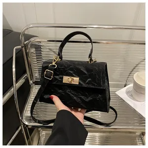 Détail du sac bandoulière noir avec texture plissée et fermoir pivotant en métal doré