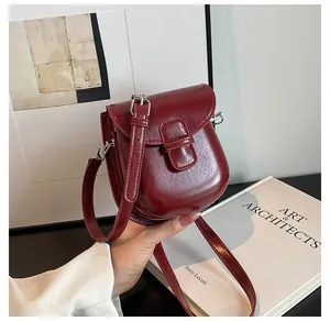 Dettaglio della borsa a tracolla in pelle lucida bordeaux con fibbia magnetica argento