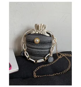 Close-up of woven bucket bag featuring pearl decor and mixed chain straps detail