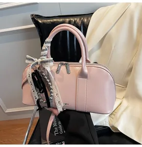 Detalle del bolso bowling rosa claro con cinta de cuadros y colgante de corazón
