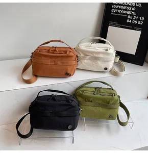 Detail view of multi-color nylon crossbody bags in caramel, white, black and green tones