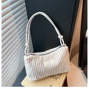 Detail of white corduroy tote bag showing striped texture and zip closure on prop books