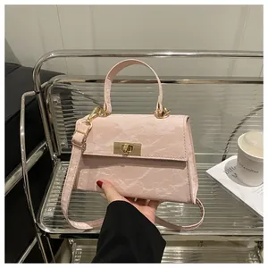 Détail du sac bandoulière rose clair avec texture plissée et boucle de verrouillage dorée