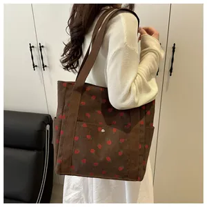 Detail of strawberry print corduroy tote bag showing metal snap button and side pocket