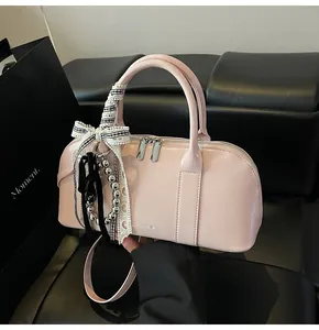 Detalle del bolso en charol rosa claro con lazo decorativo y accesorio de cuentas