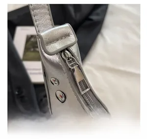 Close-up of silver leather moon bag featuring metallic rivets and a smooth metal zipper