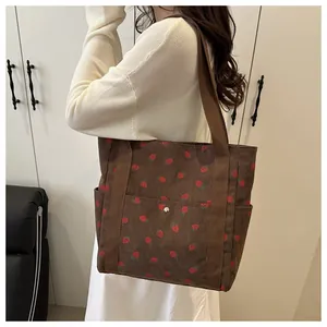 Detail of corduroy tote bag with strawberry print showing side pockets and fabric texture
