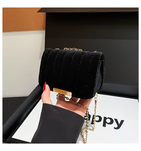 Detalle de bolso bandolera de terciopelo negro con cadena dorada y brillo acolchado