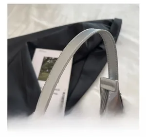 Close-up of silver-grey bag showing metal studs and smooth arc-shaped handle detail